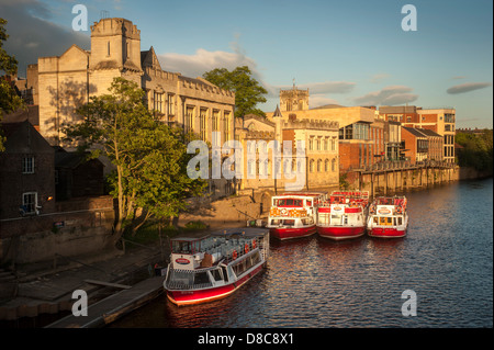 River Ouse avec une flotte de bateaux de croisière et de location de touristes amarrés le long du Guildhall lors d'une soirée d'été ensoleillée à York. Banque D'Images