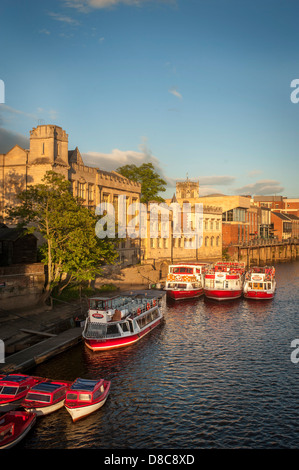 River Ouse avec une flotte de bateaux de croisière et de location de touristes amarrés le long du Guildhall lors d'une soirée d'été ensoleillée à York. Banque D'Images