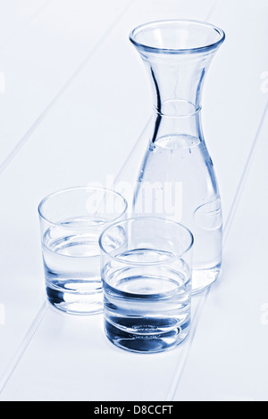 Carafe à eau et 2 verres - une carafe d'eau sur une table avec deux verres, dans les tons bleu. Banque D'Images