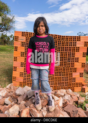 Une jeune fille hispanique s'élève face à une pile de blocs de construction en céramique pour la construction domiciliaire dans un bâtiment d'accueil du site. Banque D'Images