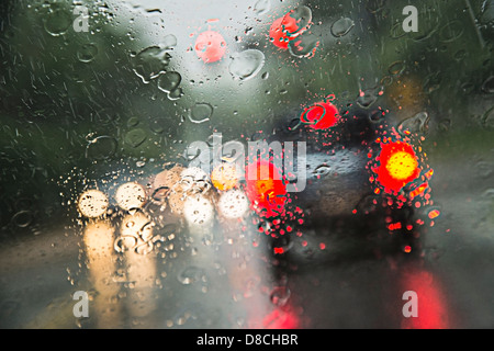 La pluie sur le pare-brise avec les voitures qui circulent dans la tempête de pluie Banque D'Images