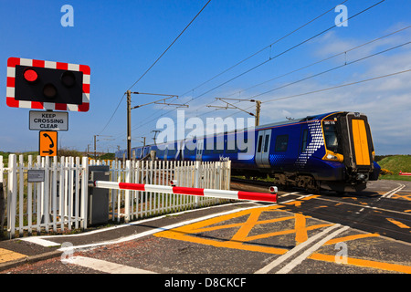 Train électrique traversant un passage contrôlé, montrant les feux de circulation et de contrôle barrière, Ayrshire, Scotland, UK Banque D'Images