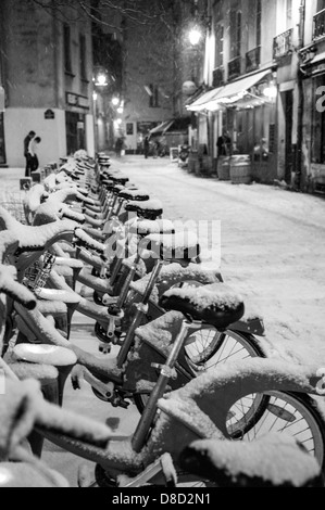 Vélos couvert de neige dans la station de Velib de Paris. Banque D'Images