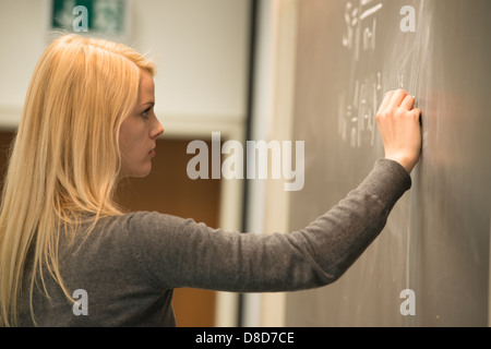 Étudiante inscrite à l'avant du tableau noir, l'écriture de formules mathématiques Banque D'Images