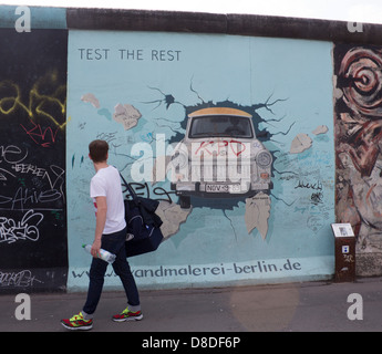 Mur de Berlin East Side Gallery peinture de voiture Trabant briser mur avec man walking passé, retour à Berlin Allemagne Banque D'Images