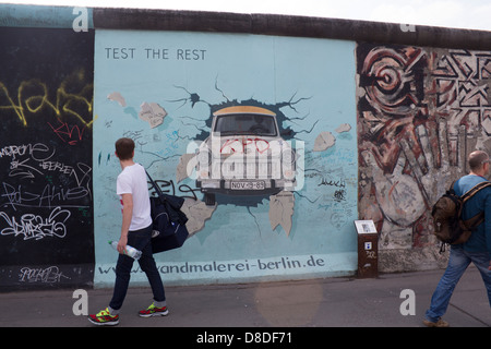 Mur de Berlin East Side Gallery peinture de voiture Trabant briser mur avec man walking passé, retour à Berlin Allemagne Banque D'Images