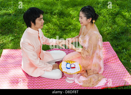 Thai asiatique mariée porte anneau de mariage à son époux en thaï cérémonie avec sentiment de bonheur. Banque D'Images