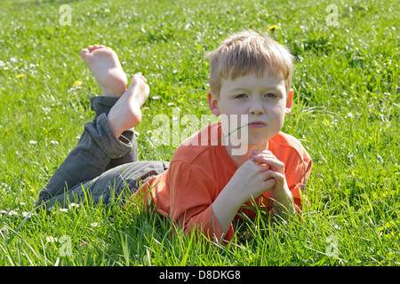 Portrait d'un jeune garçon profitant du beau temps couchée dans un pré Banque D'Images