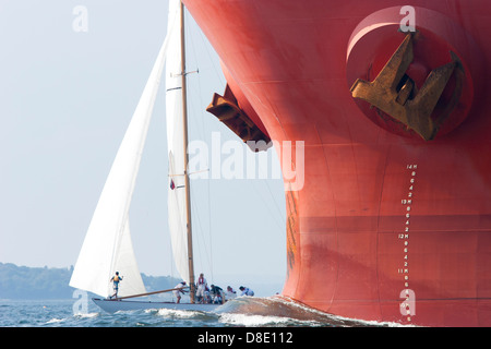 La proue d'un grand cargo qui pousse dans l'eau et traverse un bateau à voile dans la baie de Narragansett dans Rhode Island Banque D'Images