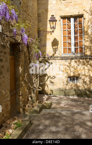 Lampadaire en fer forgé d'après-midi sur le mur de l'ombre des bâtiments en pierre médiévale dans la cour, Sarlat, Dordogne, France Banque D'Images