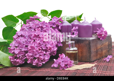 Décorées de fleurs de lilas mauve, des bougies et de l'huile pour se détendre Banque D'Images