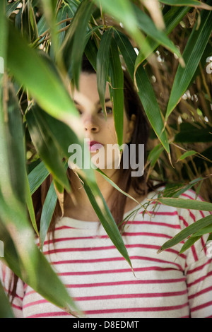 Woman Peering à travers la verdure Banque D'Images