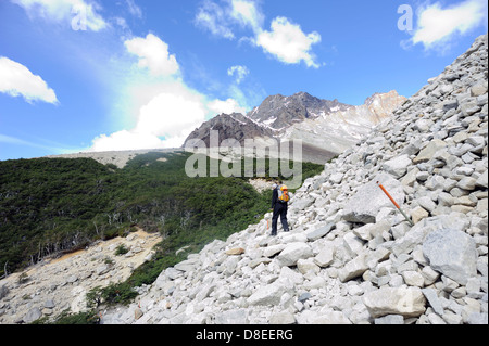 Une marchette descend le chemin balisé au Mirador Las Torres et les flèches de granit du Torres del Paine. Banque D'Images