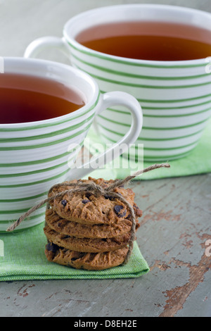 Libre de cookies aux pépites de chocolat et deux tasses de thé sur fond de bois vintage Banque D'Images