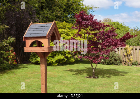 Tableau d'oiseaux en bois avec un toit en ardoise et un Acer arbre sur un jardin à l'arrière pelouse au soleil d'été. Royaume-uni, Angleterre Banque D'Images