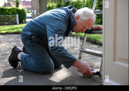 75 ans de peinture pensionné le porche de sa maison à North Yorkshire, England, UK Banque D'Images