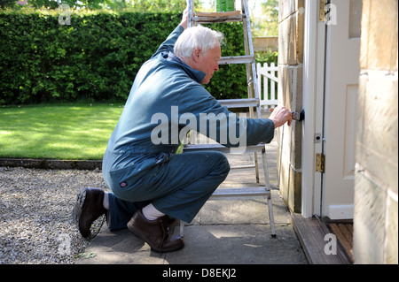 75 ans de peinture pensionné le porche de sa maison à North Yorkshire, England, UK Banque D'Images