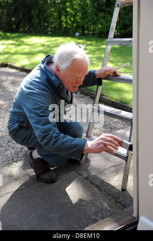 75 ans de peinture pensionné le porche de sa maison à North Yorkshire, England, UK Banque D'Images