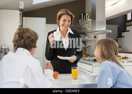 Mère et enfants de prendre le petit déjeuner avant le travail et l'école Banque D'Images