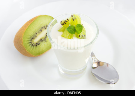 Yaourt frais avec kiwi (fruit) dans bécher en verre blanc, gros plan sur la plaque horizontale, copy space Banque D'Images