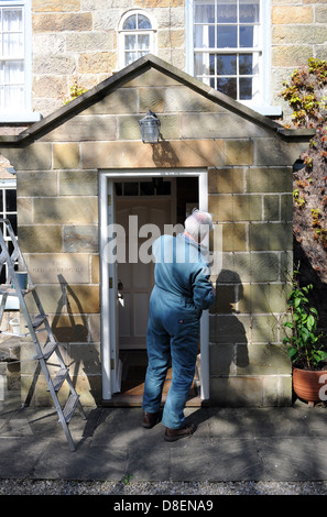 75 ans de peinture pensionné le porche de sa maison à North Yorkshire, England, UK Banque D'Images