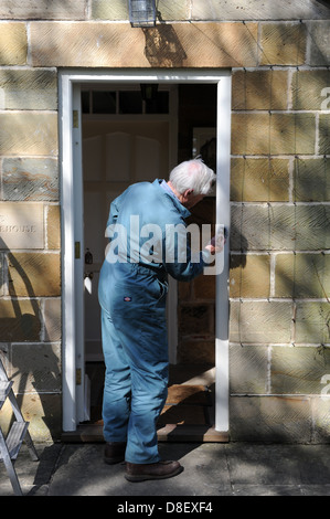 75 ans de peinture pensionné le porche de sa maison à North Yorkshire, England, UK Banque D'Images