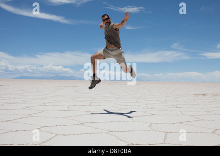 Homme passe dans le sombre paysage blanc du Salar de Uyuni en Bolivie Banque D'Images