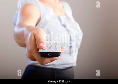 Femme d'affaires possède une télécommande dans ses mains avec son corps n'est pas mise au point Banque D'Images