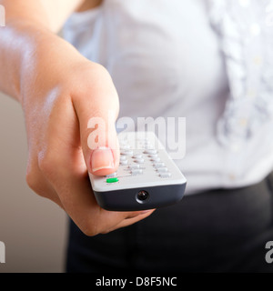 Femme d'affaires possède une télécommande dans ses mains avec son corps n'est pas mise au point Banque D'Images