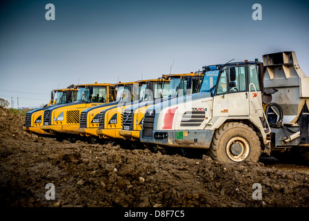 Rangée de camions à benne basculante sur le site prête à enlever le sol excavé d'un chantier de construction. Banque D'Images