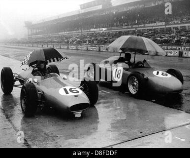 Pilote de Formule 1 Australien Jack Brabham (l) et son collègue Graf Carel de Beaufort (r) se protéger avec parasols contre la pluie le 5 août en 1962 avant le début du Grand Prix d'Allemagne au Nürburgring. Banque D'Images