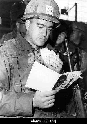 Un soldat de l'armée américaine est en train de lire un livre sur les habitudes allemandes lors de son arrivée à partir de la France le 21 janvier 1969 à l'aéroport de Nuremberg. Le livre a été donné aux soldats de l'armée. Les soldats participent à la manœuvre REFORGER I - Retour des forces de l'Allemagne. Environ 17 000 militaires ont participé à la manœuvre, beaucoup d'entre eux ont été amenés à l'Allemagne par pont aérien. L'équipement des soldats est enregistré pour la plupart dans des dépôts en Allemagne. Banque D'Images