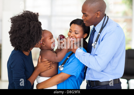 Friendly nurse holding bébé qui pleure avec mère et médecin Banque D'Images