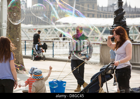 Les enfants bulles chasse faite par un artiste de rue sur la rive sud de Londres. Banque D'Images