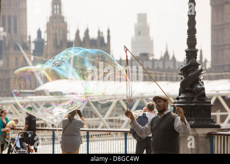 Les enfants bulles chasse faite par un artiste de rue sur la rive sud de Londres. Banque D'Images