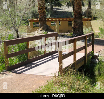 Un pont traverse un petit ruisseau, menant à un sentier pittoresque à travers les bois. Le sentier offre une escapade paisible en plein air entouré par la nature. Banque D'Images