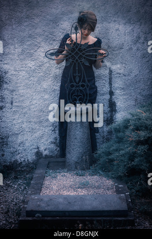 Une femme en deuil avec voile et robe sombre sur un cimetière Banque D'Images