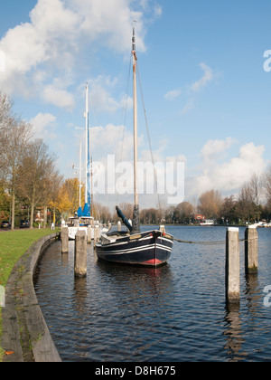 Petit bateau à voile en bois amarré sur la rivière spaarne Haarlem en hivers sur une journée ensoleillée avec ciel bleu et nuages blancs Banque D'Images