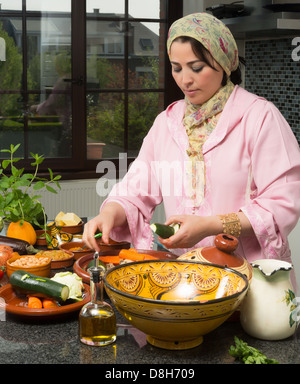 Femme immigrée marocaine dans la cuisine européenne moderne préparer un plat tajine traditionnel pour les nuits du Ramadan Banque D'Images