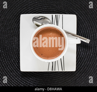 Boire un chocolat chaud dans la tasse et soucoupe blanc sur noir tapis Banque D'Images