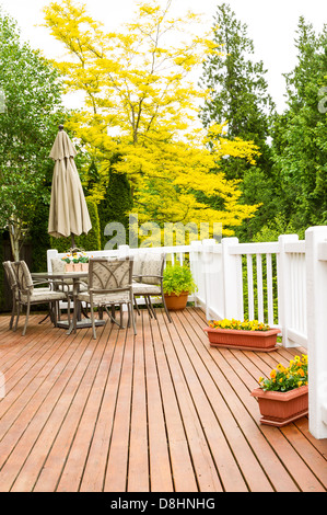 Photo verticale d'une grande piscine en bois de cèdre naturel avec mobilier de terrasse et d'un jaune vif et vert des arbres en arrière-plan Banque D'Images