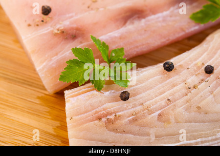 Photo horizontale gros plan de filets de poisson blanc, le persil et le poivre de voirie sur fond de bois de bambou naturel Banque D'Images