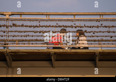 Paris, France. Un couple est assis sur le pont à pont des arts, couverts de cadenas symbolisant l'amour et des relations. Banque D'Images