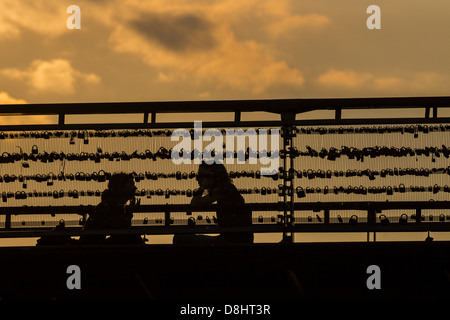 Paris, France. Un couple est assis sur le pont à pont des arts, couverts de cadenas symbolisant l'amour et des relations. Banque D'Images