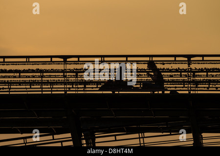 Paris, France. Un couple est assis sur le pont à pont des arts, couverts de cadenas symbolisant l'amour et des relations. Banque D'Images