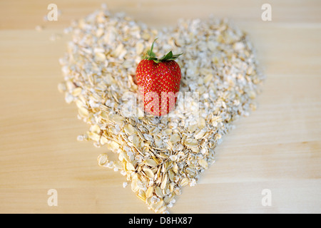 Une fraise sur un tas de flocons d'avoine dans une forme de coeur Banque D'Images