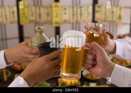 Quatre personnes Toasting les uns avec les autres avec des boissons diverses à l'izakaya Banque D'Images