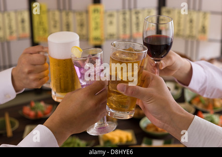 Quatre personnes Toasting les uns avec les autres avec des boissons diverses à l'izakaya Banque D'Images