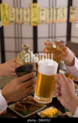 Quatre personnes Toasting les uns avec les autres avec des boissons diverses à l'izakaya Banque D'Images