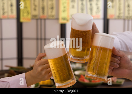 Trois personnes Toasting with Beer à l'izakaya Banque D'Images